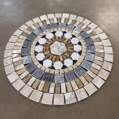 Rosace en marbre et travertin AL-2443 (vue de biais sur fond gris) composée de rectangles, de carrés, d'hexagones et de losanges de tailles différentes.
